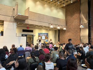 A photo shows a crowd of graduate students seated at a presentation in the Graduate Center.

