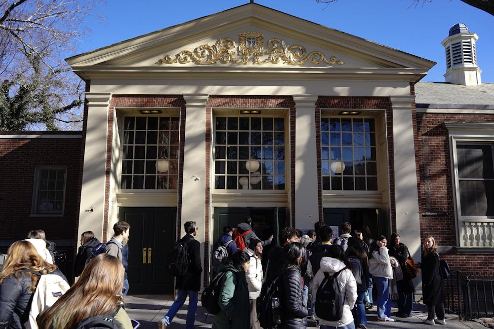 A photo showing the outside of Sharpe Refectory dining hall with people walking in and out of the front doors. 
