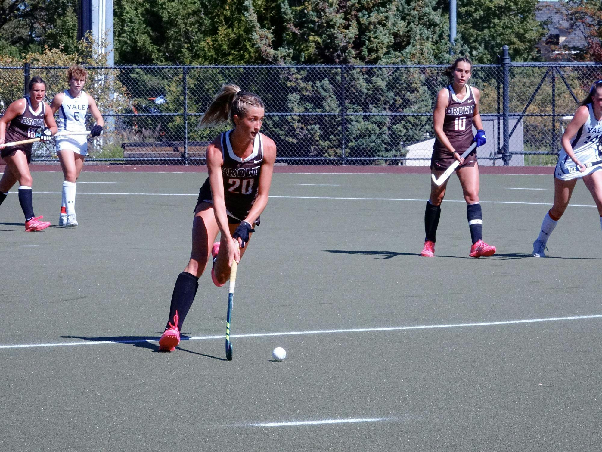 Brown playing against Yale in a field hockey match. A player from Brown is dribbling the ball.