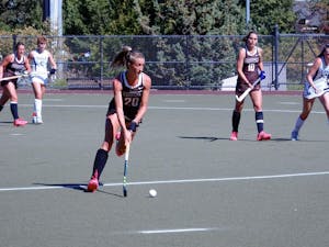 Brown playing against Yale in a field hockey match. A player from Brown is dribbling the ball.