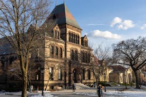A photo of Sayles Hall with barren trees in front and patches of snow on the ground surrounding it. 