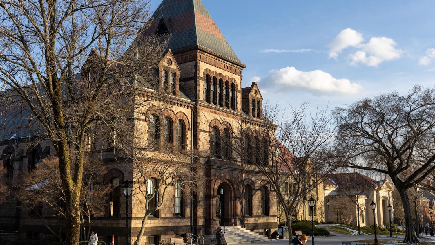 A photo of Sayles Hall with barren trees in front and patches of snow on the ground surrounding it.