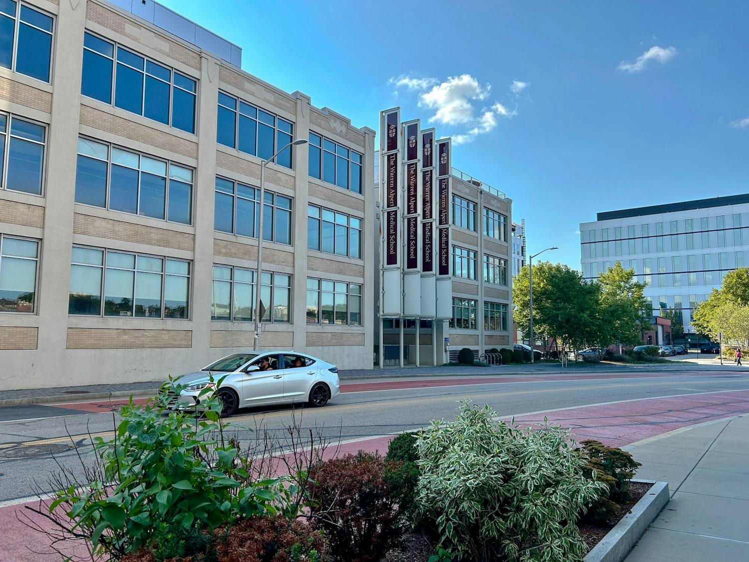 A car is parked alongside the curb in front of the Warren Alpert Medical School of Brown University, located at 222 Richmond Street.
