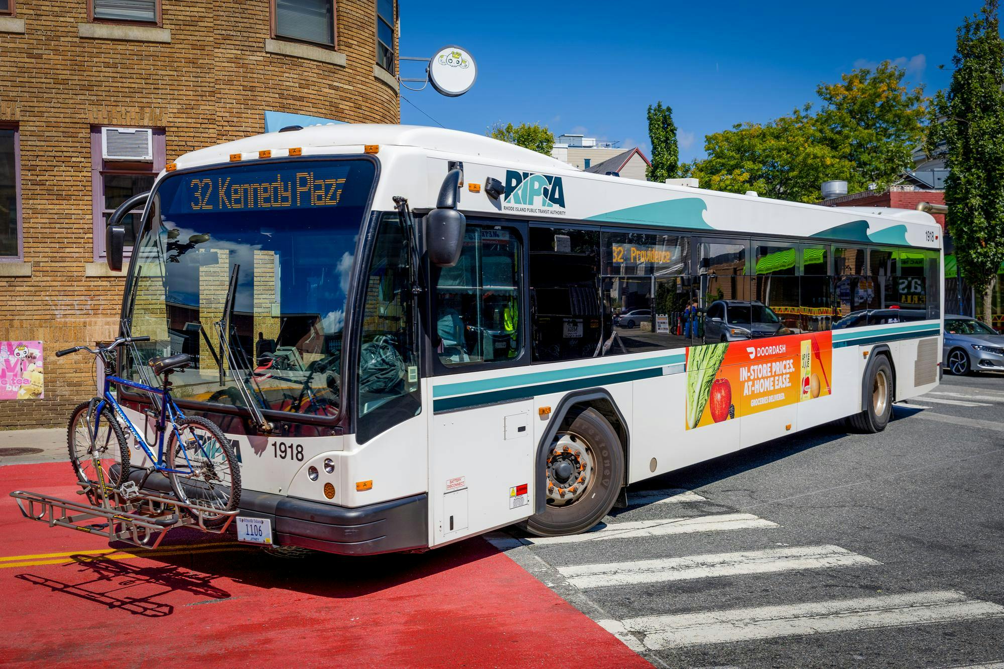 RIPTA bus turns on a curve, holding a bike on the front of the vehicle.