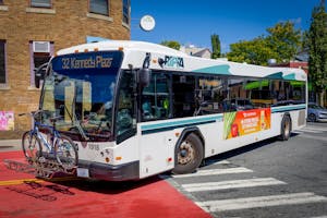 RIPTA bus turns on a curve, holding a bike on the front of the vehicle.