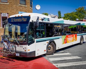 RIPTA bus turns on a curve, holding a bike on the front of the vehicle.