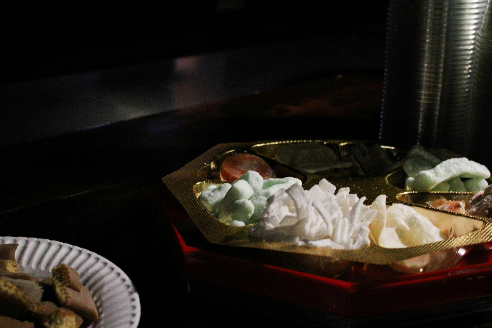 Photo of traditional Vietnamese snacks in an octagonal plate, separated into eight parts with green, white, and yellow-colored snacks.

