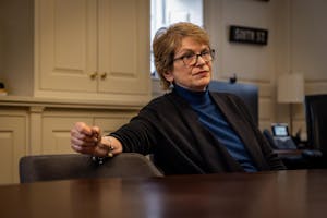 A woman with short hair sits at a table in a blue shirt.