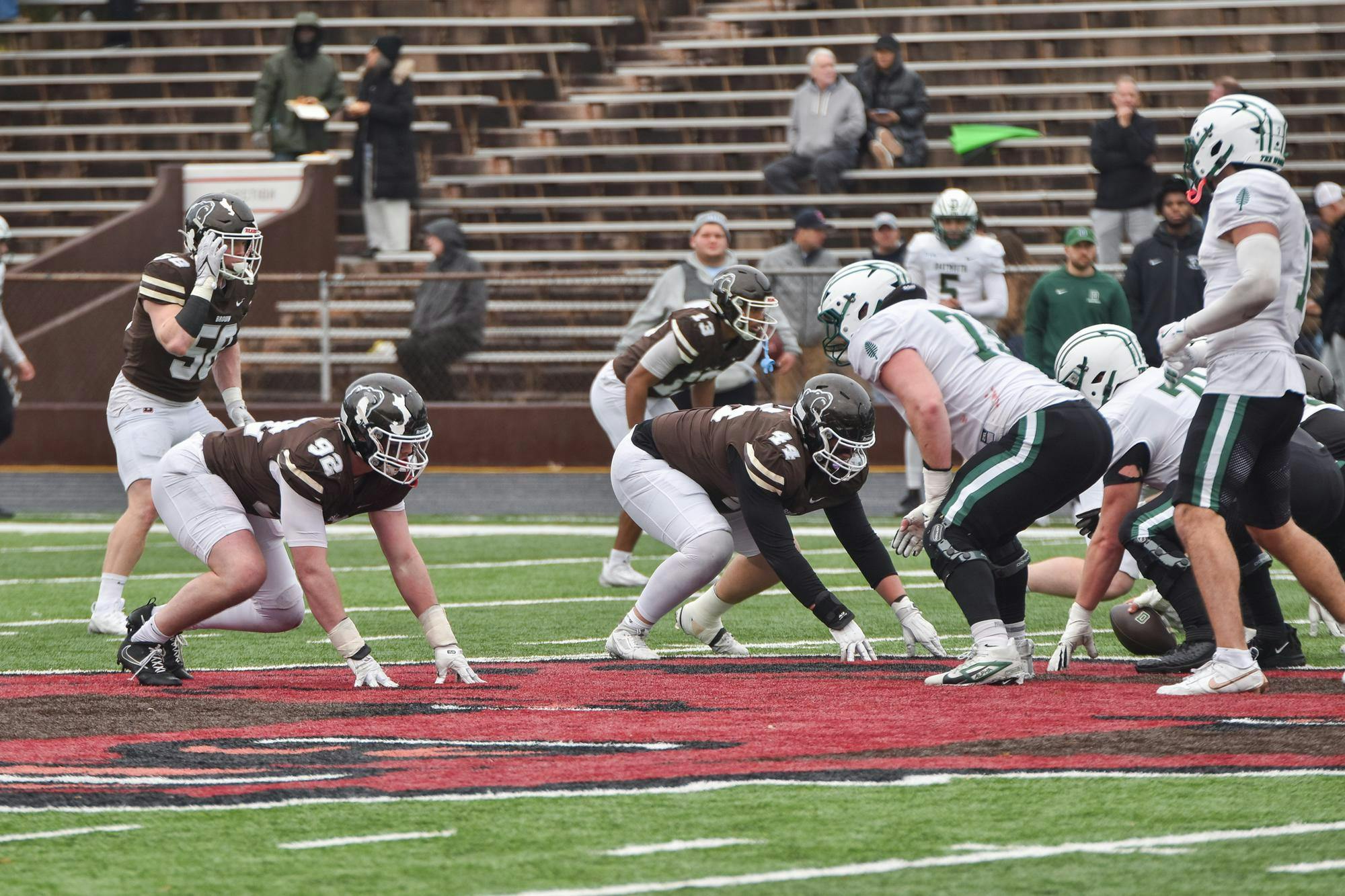 Photo of Brown and Dartmouth football players at the start of a play.