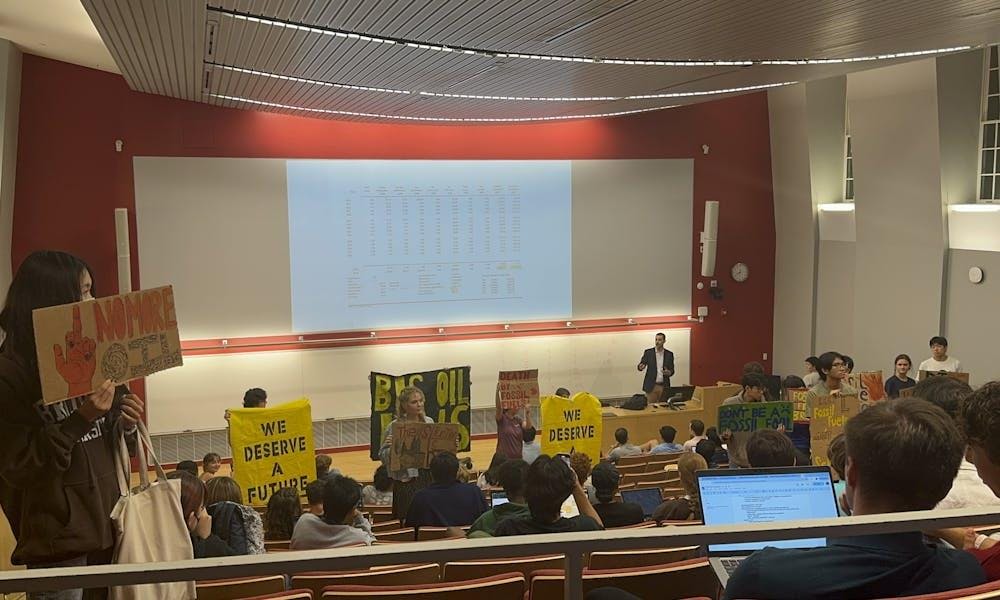 Students activists held up signs during the presentation to protest investment in fossil fuels.