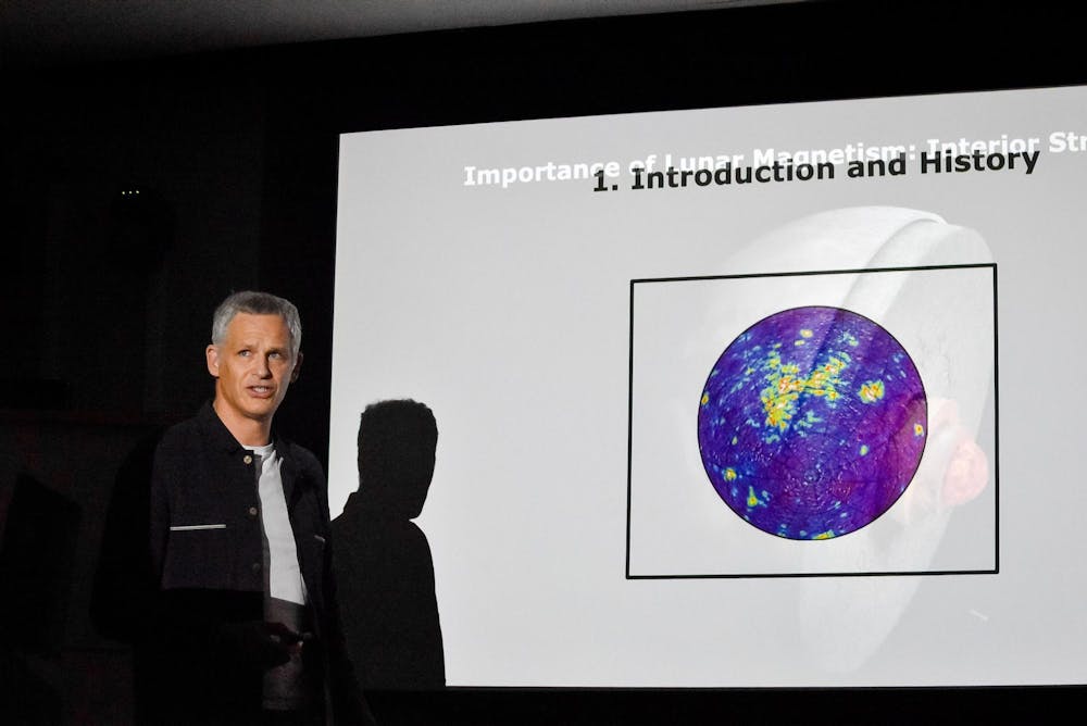 Thomas A. Mutch speaks in front of a projected slideshow.