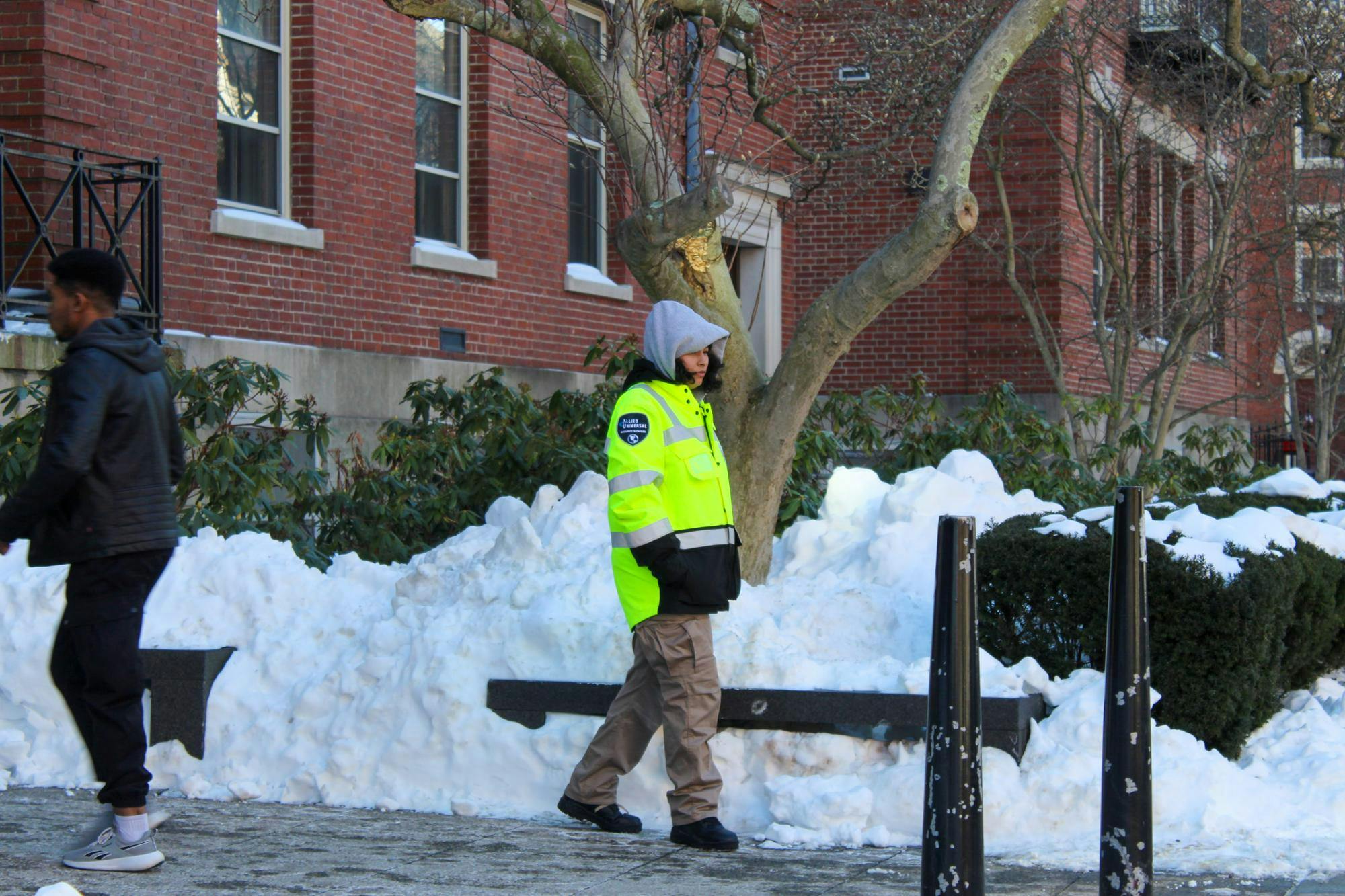 Photo of a security guard walking along a snowy sidewalk.