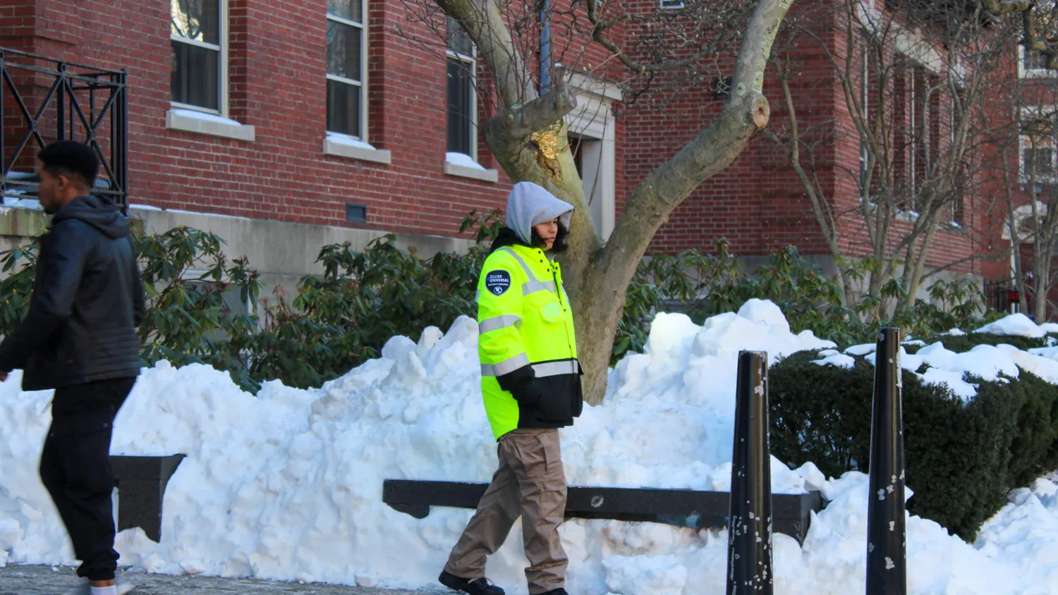Photo of a security guard walking along a snowy sidewalk.