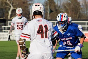 Photo of a Brown lacrosse player facing off against a University of Massachusetts at Lowell player.