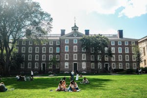 A photo of students talking on the Main Green in front of University Hall. 