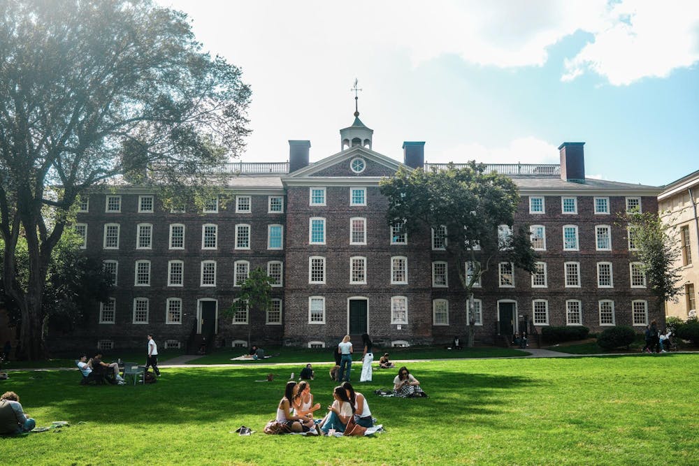 A photo of students talking on the Main Green in front of University Hall. 