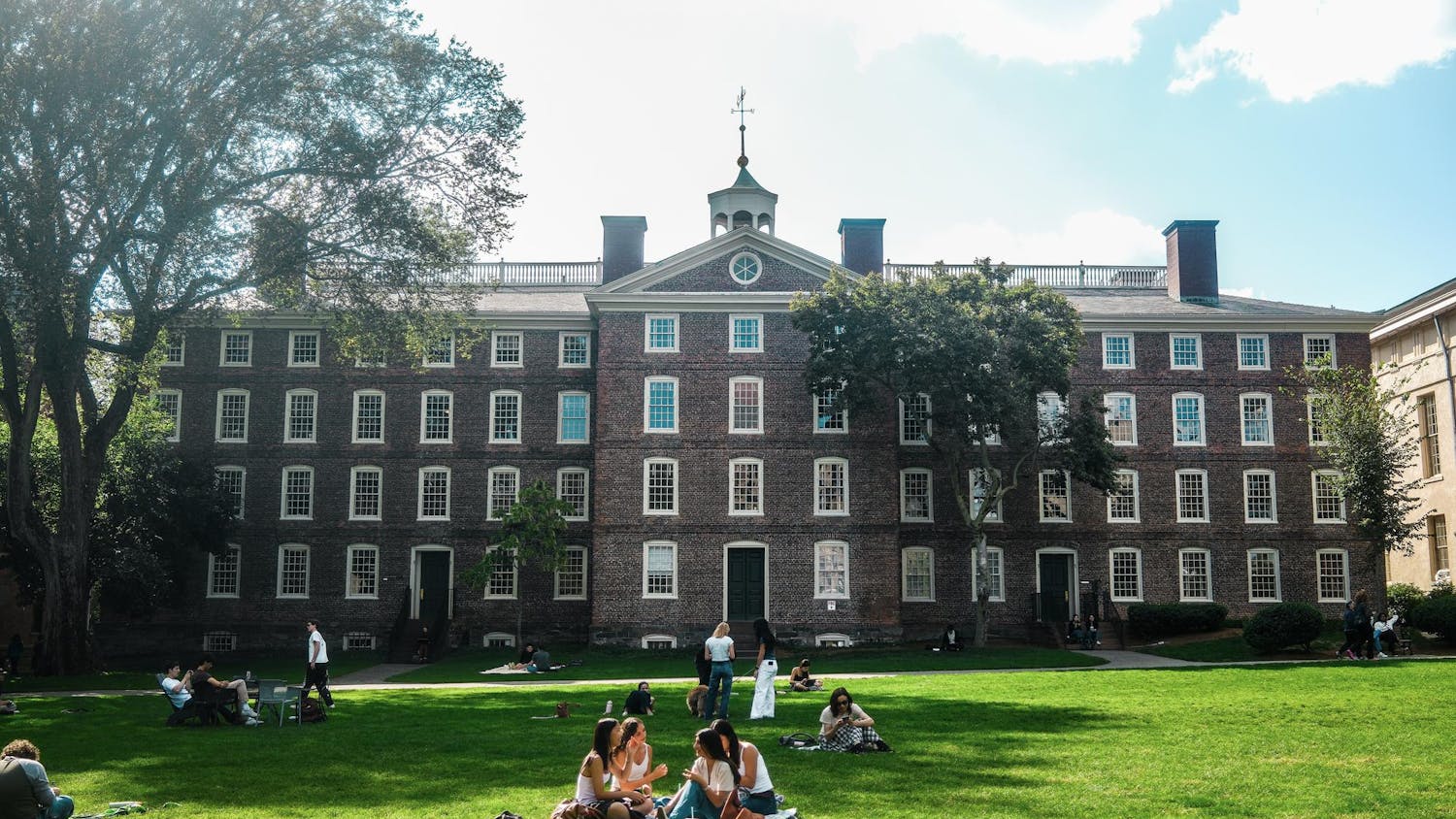 A photo of students talking on the Main Green in front of University Hall.