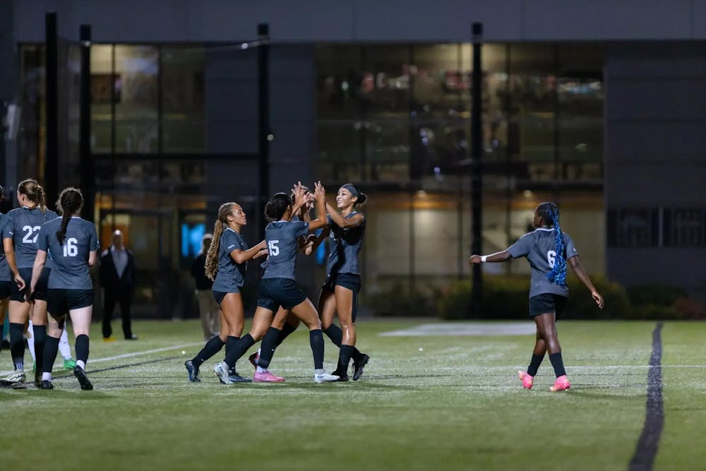 Brown Women's Soccer Team on a field with a group of players high-fiving one another