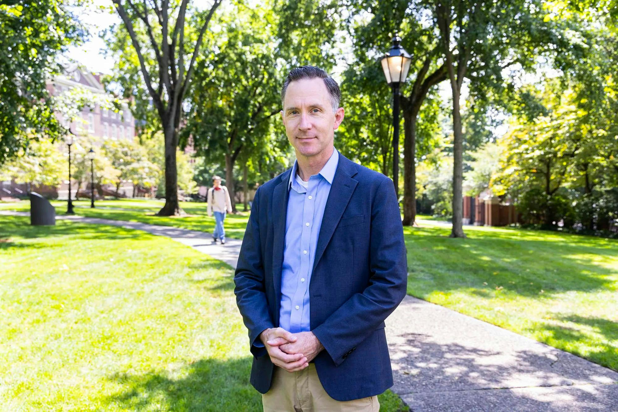 James Kellner stands in a blue suit for a portrait on the Quiet Green.

