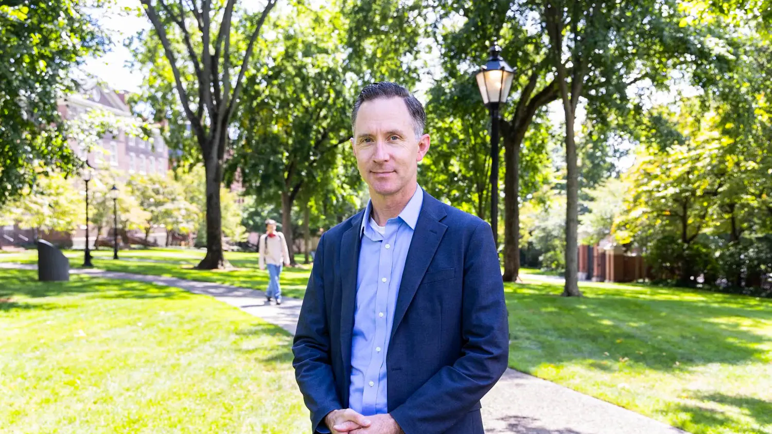 James Kellner stands in a blue suit for a portrait on the Quiet Green.