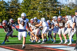Football Player Holding Ball running on turf