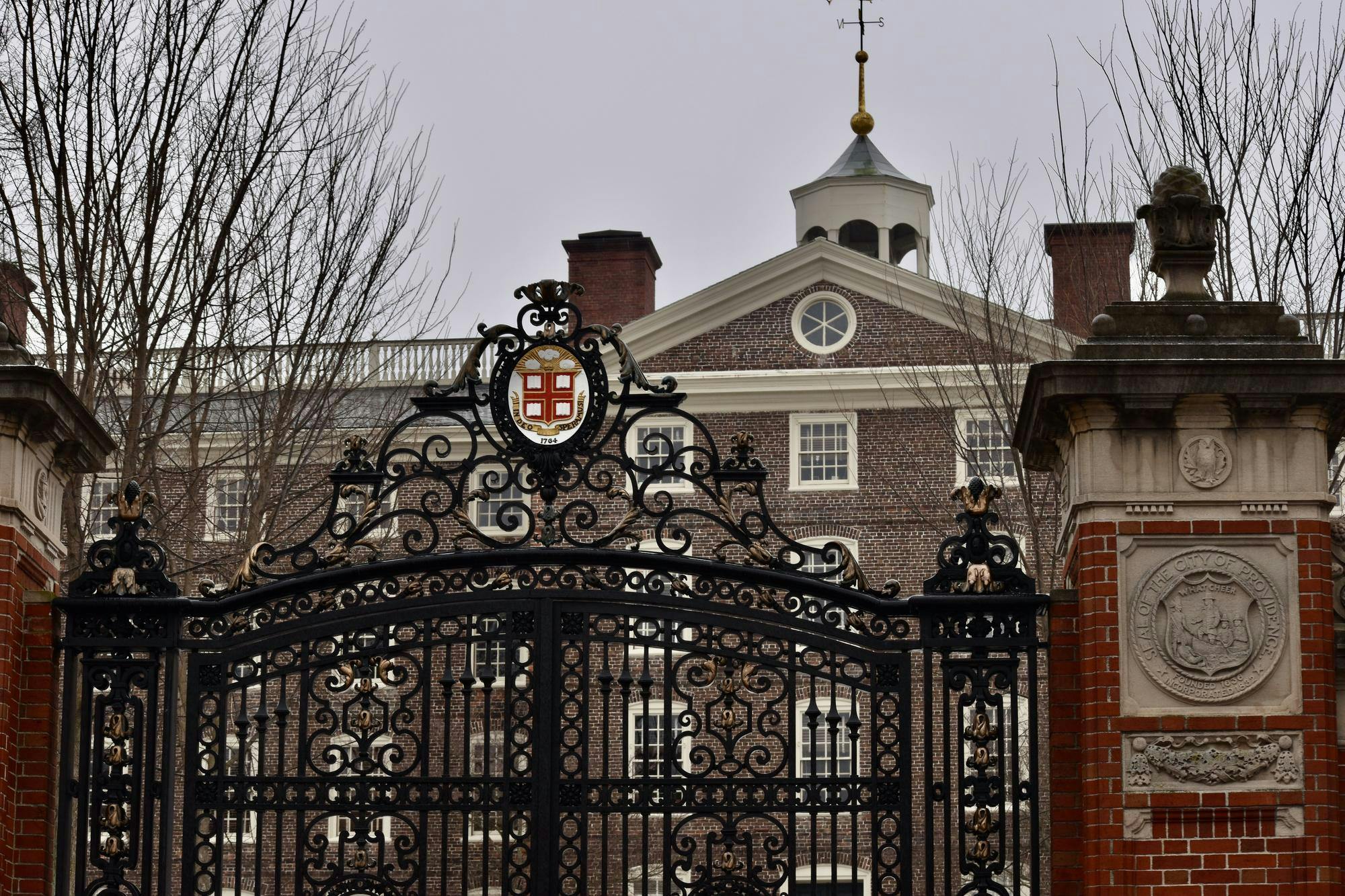 Photo of University Hall through Van Wickle Gates against a grey, cloudy sky.