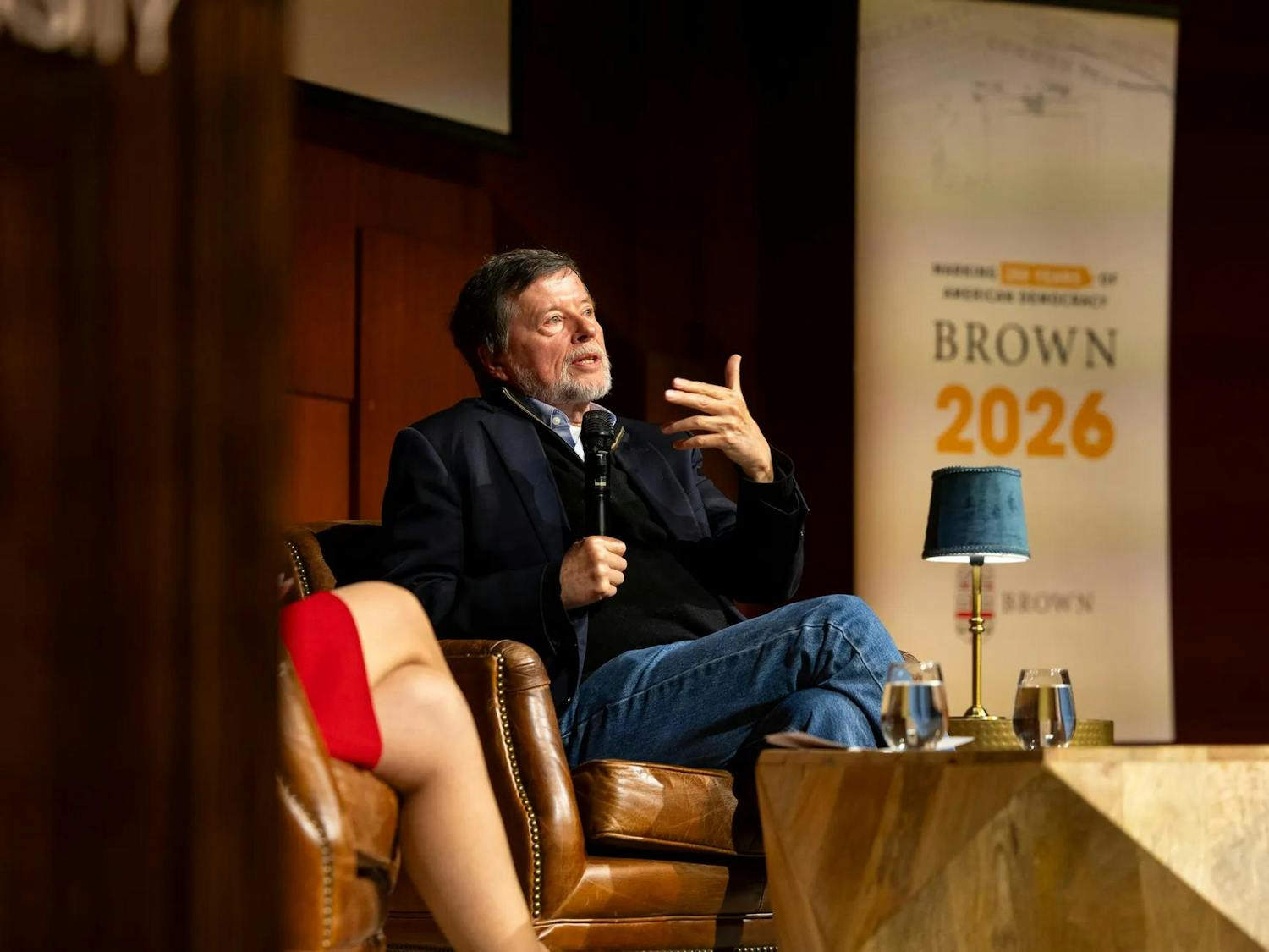 Ken Burns speaks into a microphone facing the audience onstage