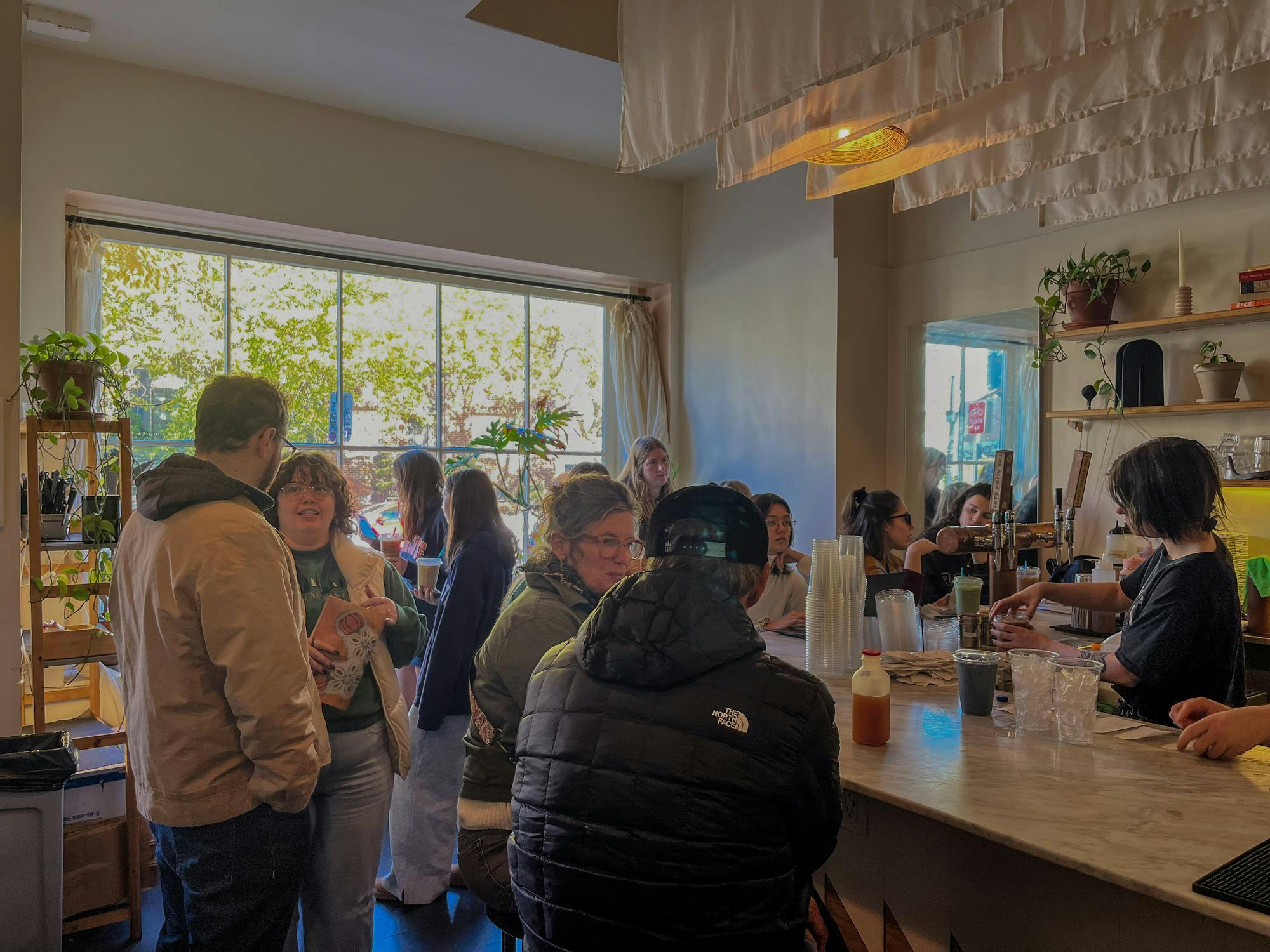 People seated and standing around the crowded coffee bar at Nitro Bar. 