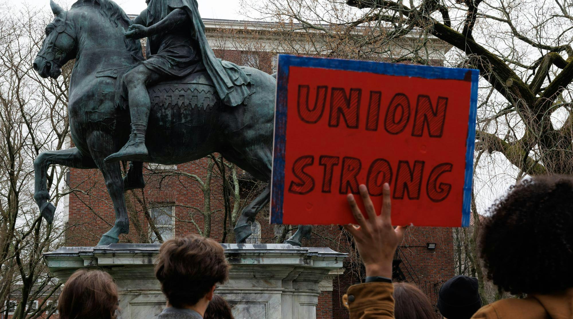 A photo of a hand holding a protest sign with the text “UNION STRONG.”