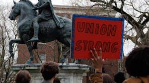 A photo of a hand holding a protest sign with the text “UNION STRONG.”