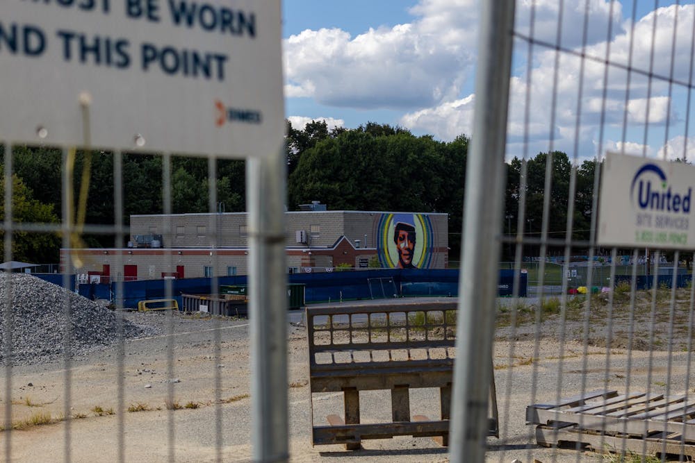 Photo of a school viewed through a gap in a silver fence