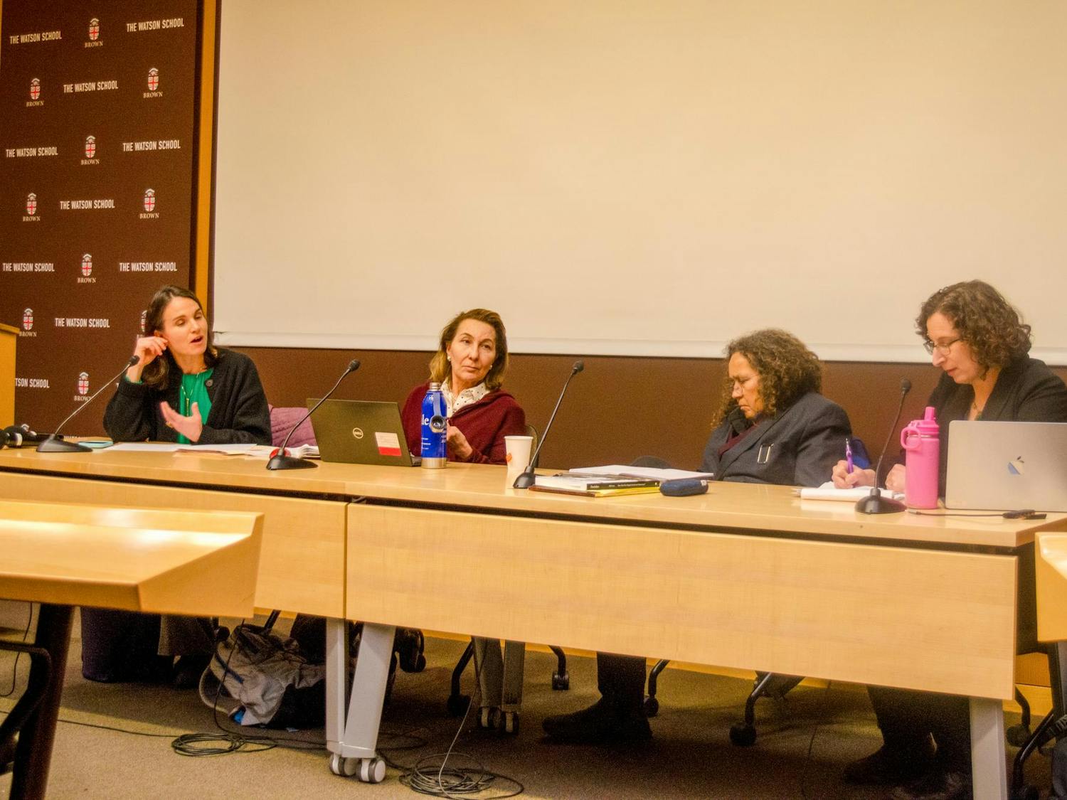 Four professors sitting at a long table in a line during a panel.