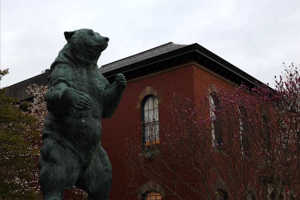 A photo of the bear statue on Brown's Main Green with Salomon Hall in the background on a cloudy day. 