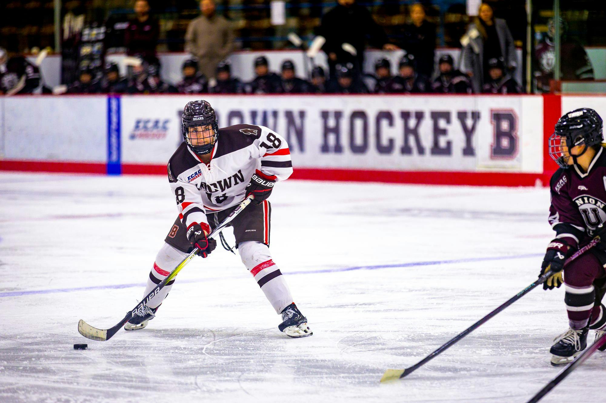 A picture of a player on the women's ice hockey team with a puck on the rink during their game against Union College.