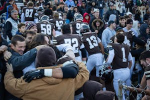 Photo of people hugging in Brown Stadium as football players exit the field.
