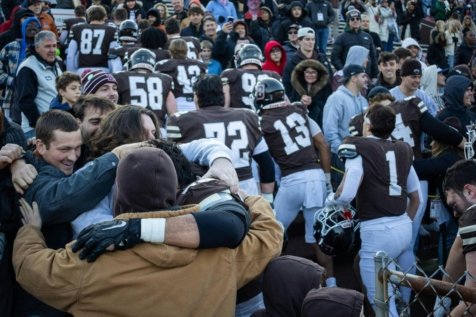 Photo of people hugging in Brown Stadium as football players exit the field.