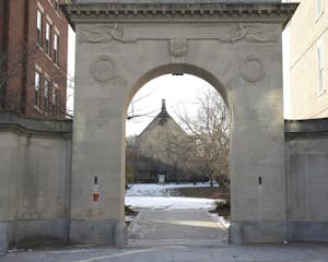 Photo shows archway that opens up onto a snow-covered quiet green.
