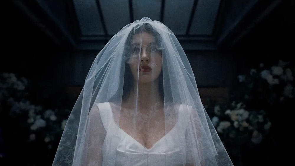 A snapshot from the show “Something Very Bad Is Going To Happen,” where the main character, Rachel, is in a wedding gown staring at something far away.