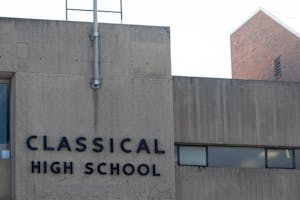 Photo of the entrance of Classical High School in Providence. The school’s title is displayed on a concrete wall near the top.

