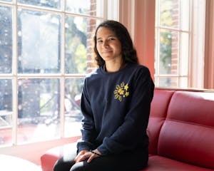 A woman sits at a window, smiling at the camera.