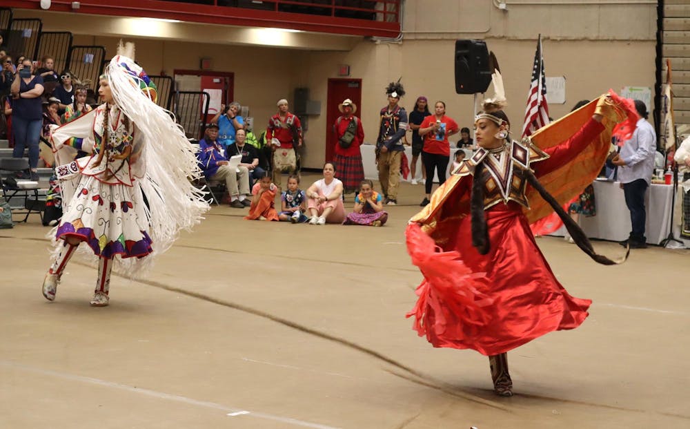 A photo of two Native American women in traditional dress dancing at the Pizzitola Sports Center.