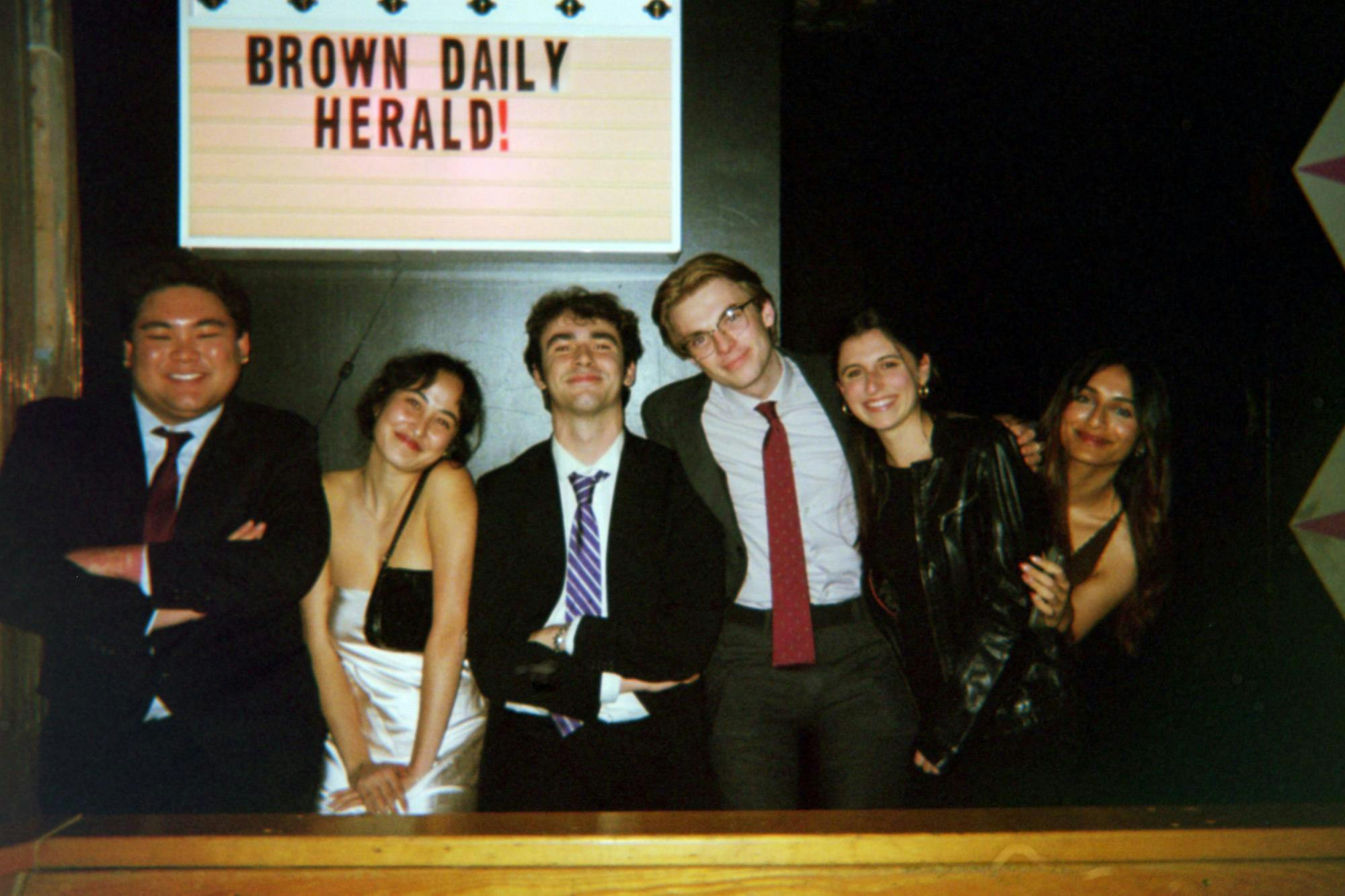 A picture of The Herald's 135th Editorial Board, standing in front of a sign that reads "Brown Daily Herald!"