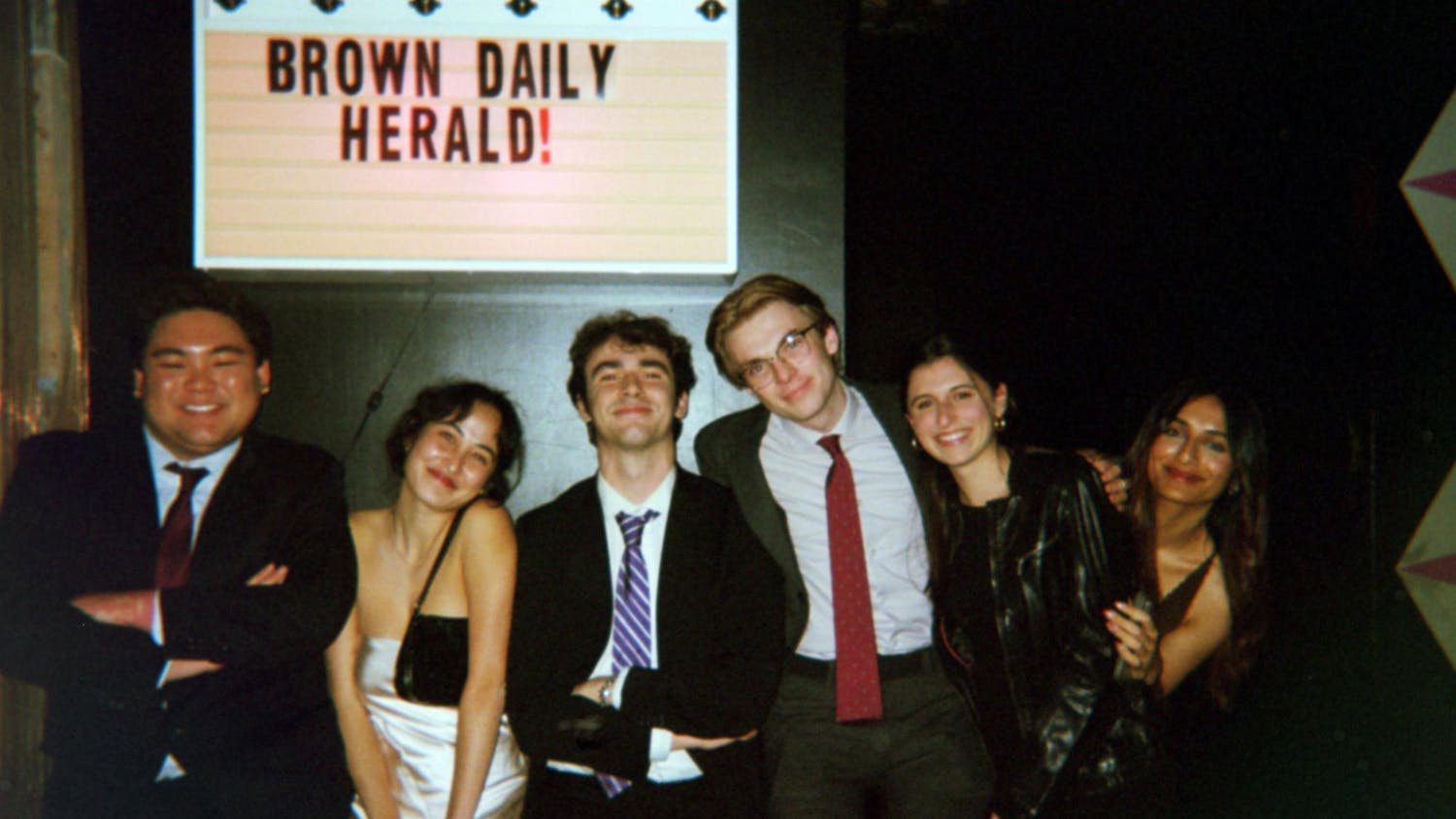 A picture of The Herald's 135th Editorial Board, standing in front of a sign that reads "Brown Daily Herald!"