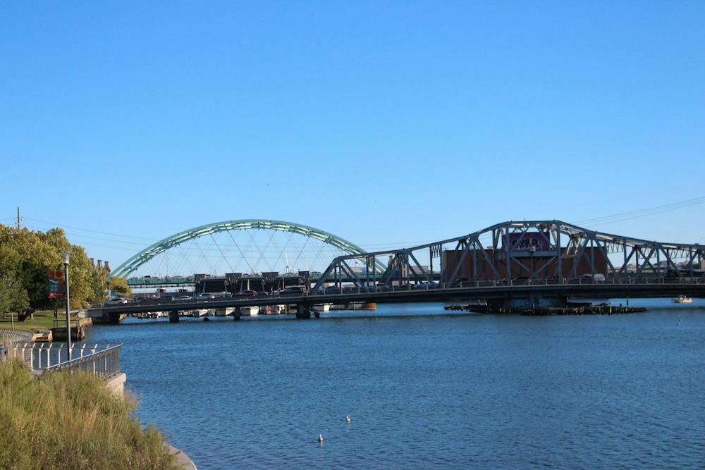 Photo of two bridges over the Providence River. The one in the back is shaped like a green semicircle and the one in the front is a grey trapezoid.