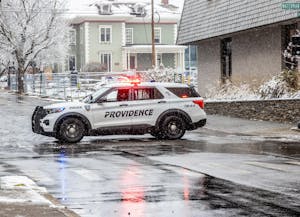 A police car drives across a snowy intersection.