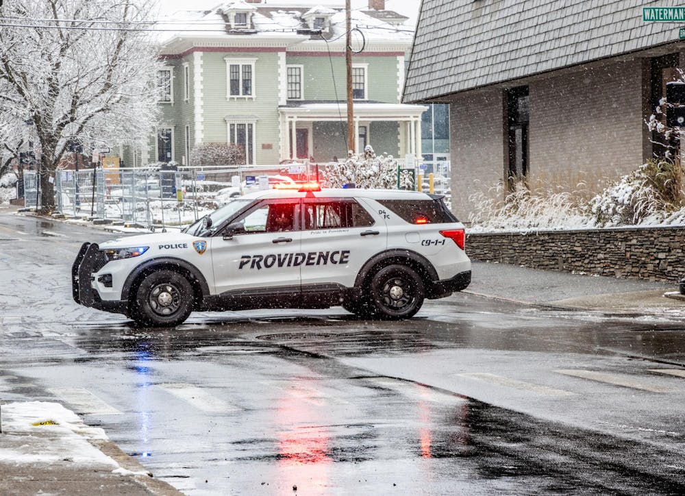 A police car drives across a snowy intersection.
