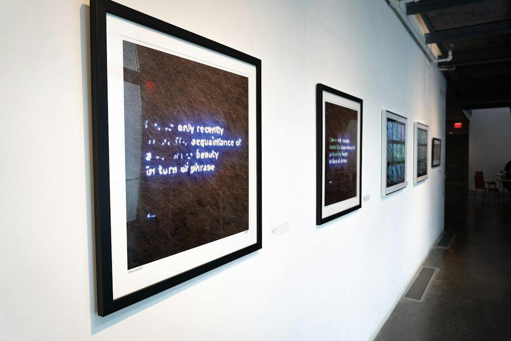 A photo of framed images showing neon word signs hung on a white wall.
