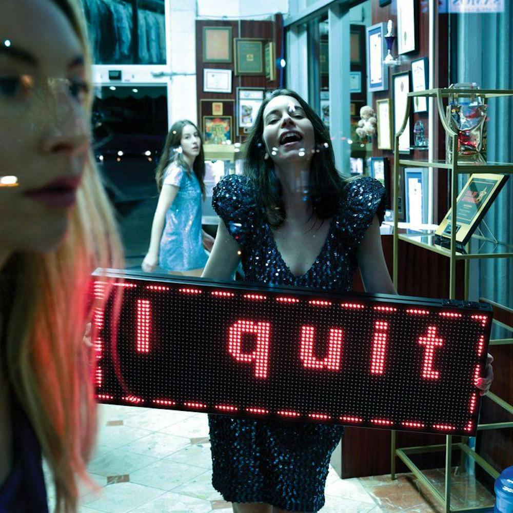 The cover of the band HAIM's latest album, "I Quit." Featuring the profile of a blond woman to the right of the image, a brunette woman in a glittery purple dress in the center, and a dark haired woman in the background wearing a blue, glittery T-shirt dress.