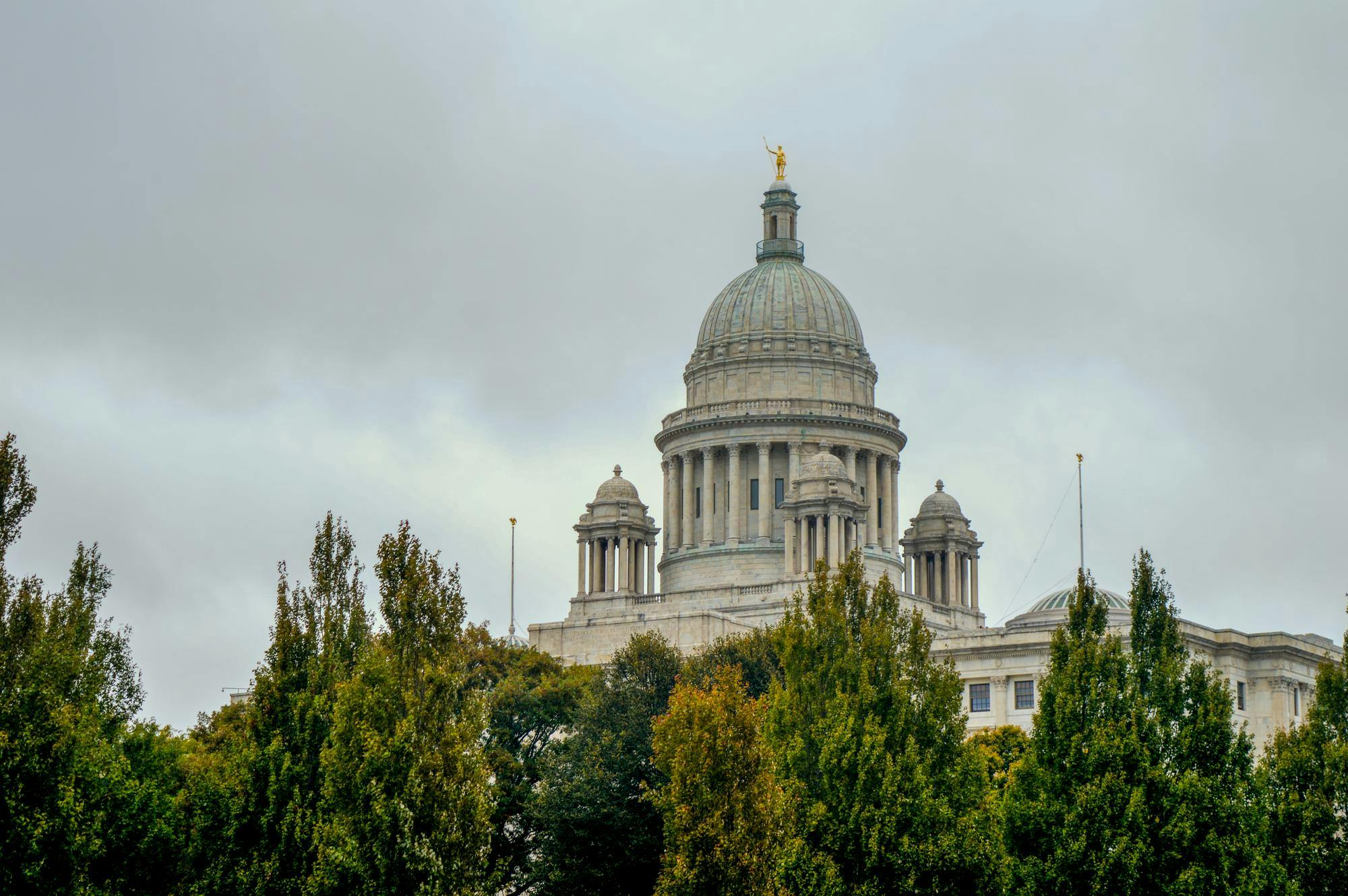 Photo of the Rhode Island State House viewed through trees.