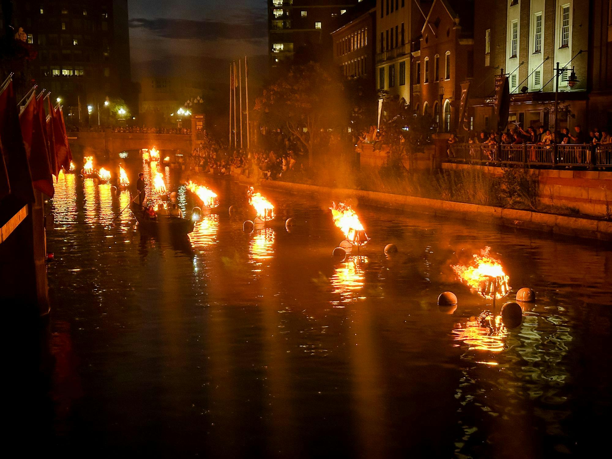 Photograph of burning braziers in a river during WaterFire
